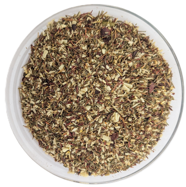 Lose Kräutertee-Mischung mit einer Basis aus grünem Rooibos, vermischt mit gehackten Mandeln, Pistazien und kleinen Kakaostücken, serviert in einer runden Glasschale.