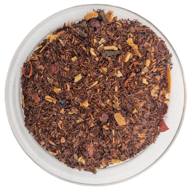 Lose Rooibos-Teemischung in einer runden Glasschale, verfeinert mit orangefarbenen Zitrusschalenstücken, getrockneten Apfelstücken, braunen Nelken und roten Beeren auf weißem Hintergrund.