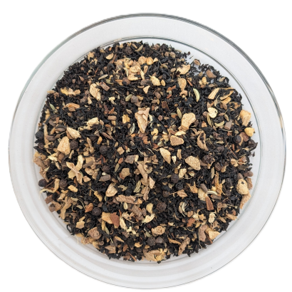 Schwarzteemischung Masala Chai in einer runden Glasschale mit dunklen Schwarzteeblättern, Ingwerstücken, Fenchelsamen und Nelken.