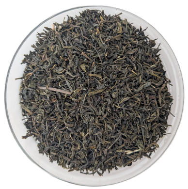 Dunkelgrün-bräunliche, feingeschnittene indische Green Khongea Grünteeblätter in einer Schale auf weißem Hintergrund.
