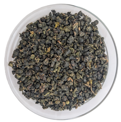 Eng gerollte, dunkelgrüne Oolong-Teeblätter aus Vietnam in einer durchsichtigen Schale auf weißem Hintergrund.