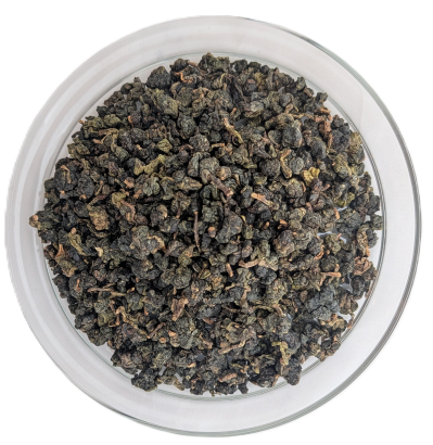 Kleine, gerollte Bio Soft Steam Oolong-Teeblätter in verschiedenen Grüntönen in einer Glasschale.