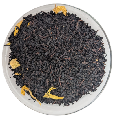 Dunkle lose Schwarzteeblätter durchsetzt mit auffälligen, leuchtend gelben Mango- oder Blütenblättern in einer Schale.