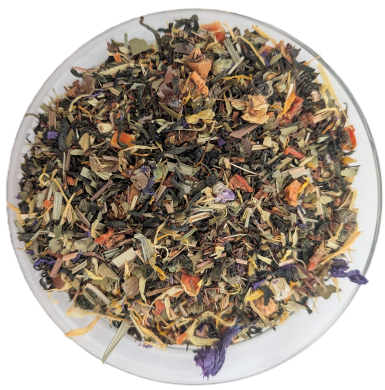 Eine bunte Teemischung Schatz der Inka in einer Glasschale mit dunkelgrünen Teeblättern, orangefarbenen Fruchtstücken, gelben Ringelblumen und violetten Blüten.