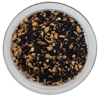 Schwarztee Vanille Chai in einer Glasschale, dunkle Teeblätter kombiniert mit hellen Ingwerstücken, Gewürznelken und grünen Kardamomkapseln.