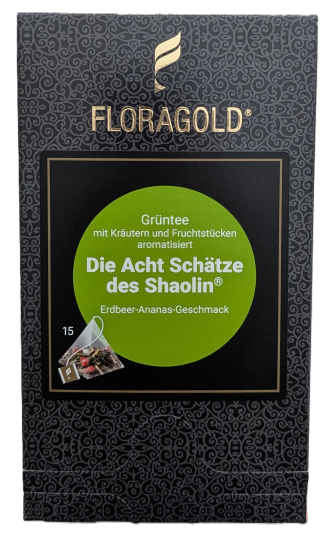 Die Verpackung von FLORAGOLD Grüntee "Die Acht Schätze des Shaolin". Sie ist dunkelgrau mit goldenem Ornamentmuster. Oben ein goldenes geflügeltes Logo und der goldene Schriftzug "FLORAGOLD". Mittig ein schwarzes Quadrat mit einem grünen Kreis. Weißer und