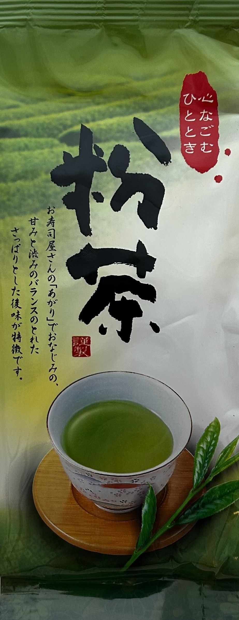 Bildstarke japanische Teeverpackung für den Konacha aus Shizuku No. 1. Der Hintergrund zeigt im oberen Bereich eine fotorealistische, sanft weichgezeichnete Aufnahme von üppig grünen, terrassierten Teefeldern. Im Zentrum dominieren sehr große, kraftvolle