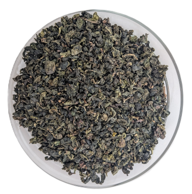 Eng zu kleinen, olivegrünen Kügelchen gerollte Bio-Ti-Guan-Yin-Oolong-Teeblätter in einer Schale.